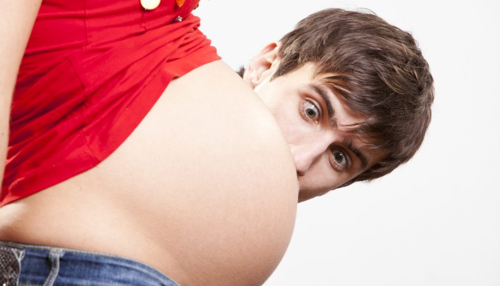 Surprised man peek out from behind the pregnant belly