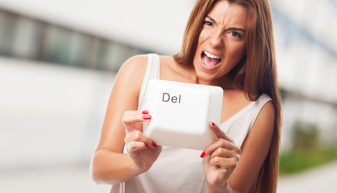 A young woman holding a delete key of a keyboard